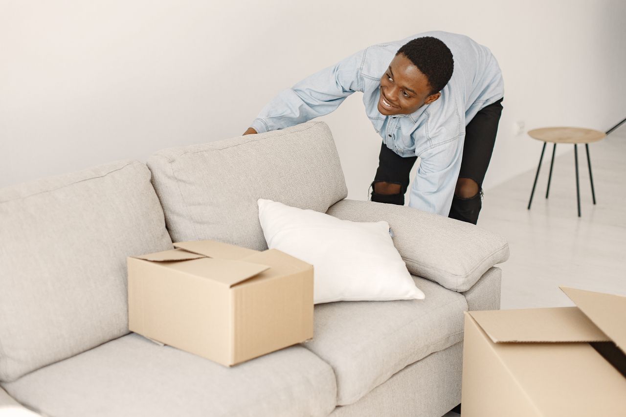 about-02 Jeune homme souriant en train d'organiser des cartons dans un salon moderne.